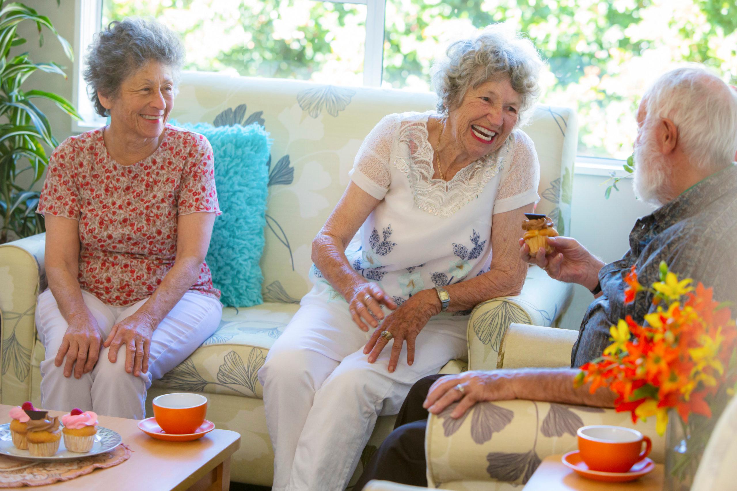 Three rest home residents laughing with cake